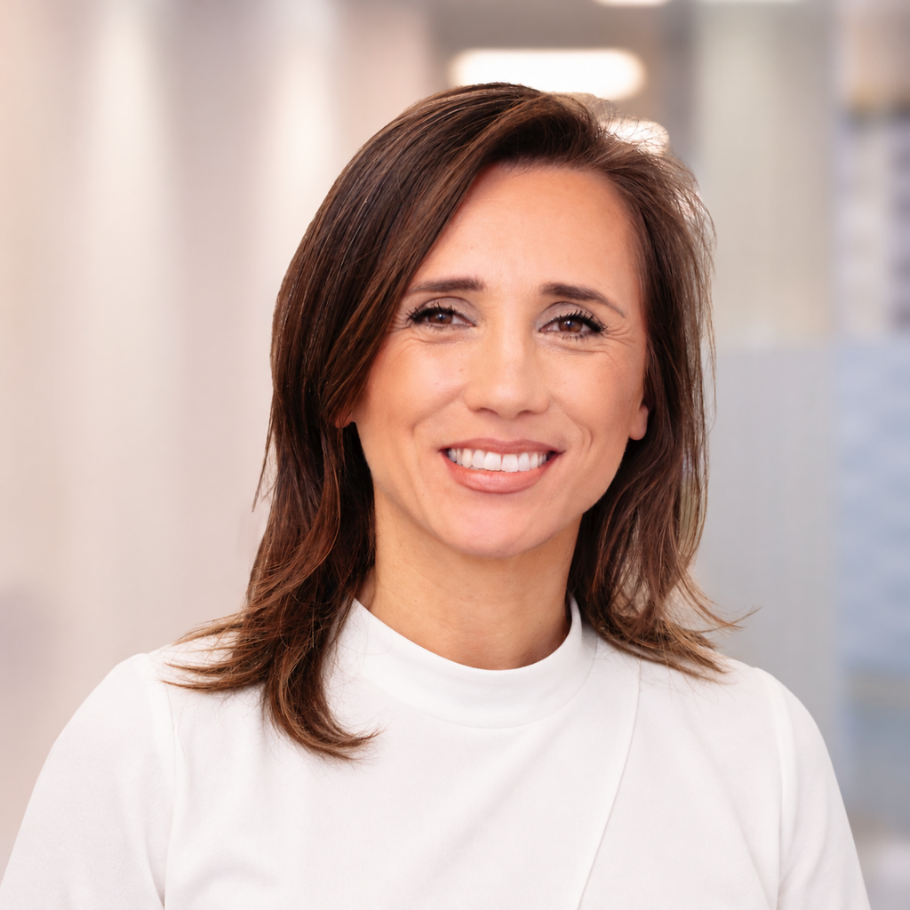 Head-and-shoulders portrait of Livia Bernardini smiling, in a white high-neck top, against a softly lit office background